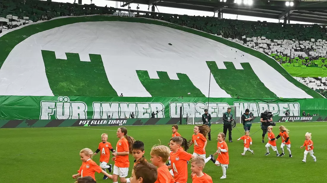 Das neue alte Wappen des VfL Wolfsburg wird vor dem Spiel gegen Bayern München stolz von den Fans präsentiert. - Bild: Swen Pförtner/dpa