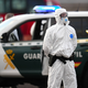 Die Sicherheitsvorkehrungen sind hoch: Ein Mitglied der Guardia Civil, das einen weißen Schutzanzug und Maske trägt, steht auf dem Hafengelände. - Foto: AP/dpa