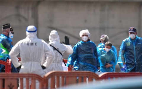 Personen in Schutzbekleidung und mit Masken gehen im Hafen von Granadilla auf Teneriffa an Land. - Foto: Manu Fernandez/AP/dpa