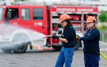 Ilias (links) und Annabella, Mitglieder der Jugendfeuerwehr in Mannheim, halten bei einer Übung einen Feuerwehrschlauch in den Händen. - Foto: Uwe Anspach/dpa