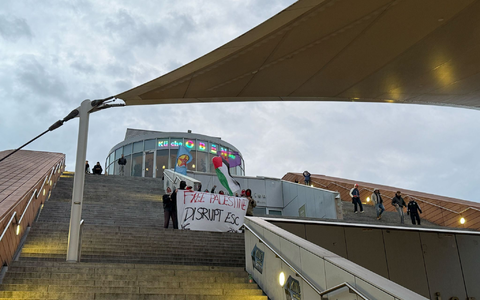Die Aktivisten protestierten mit Sprechchören und Plakaten auf den Stufen der städtischen Hauptbücherei gegen die Teilnahme Israels am ESC.  - Foto: Britta Schultejans/dpa
