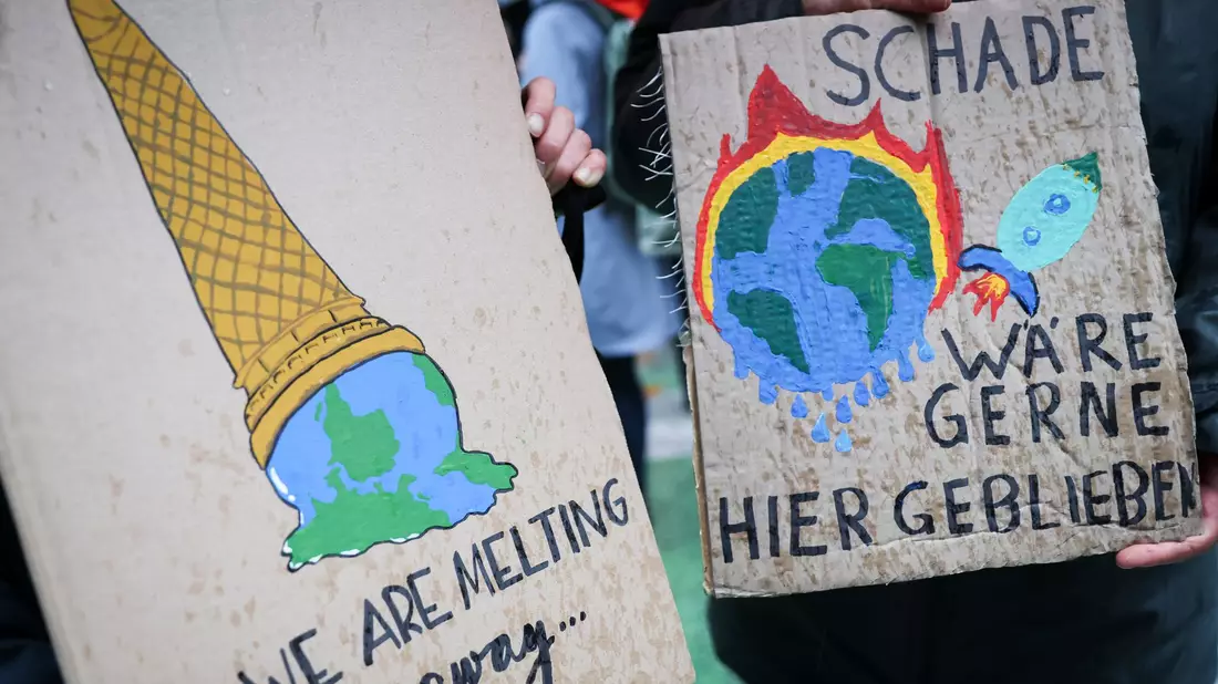 Auf einem Klimaprotest machen Plakate auf die eskalierende Krise aufmerksam. (Symbolbild) - Bild: Christian Charisius/dpa