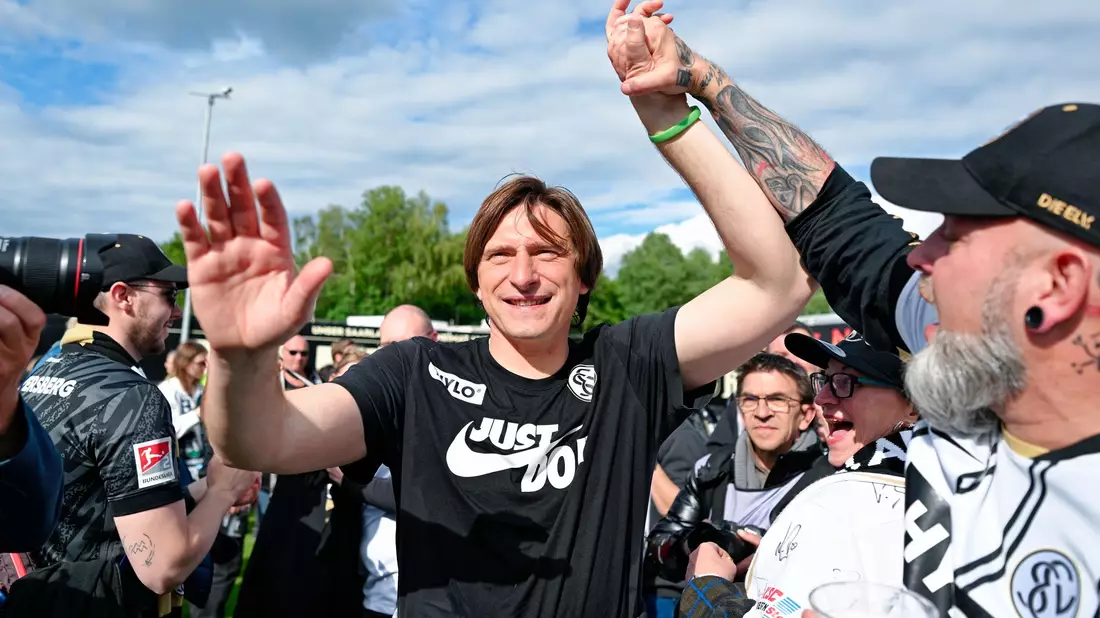 Elversberg-Coach Vincent Wagner jubelt mit den Fans über den Aufstieg.  - Bild: Uwe Anspach/dpa