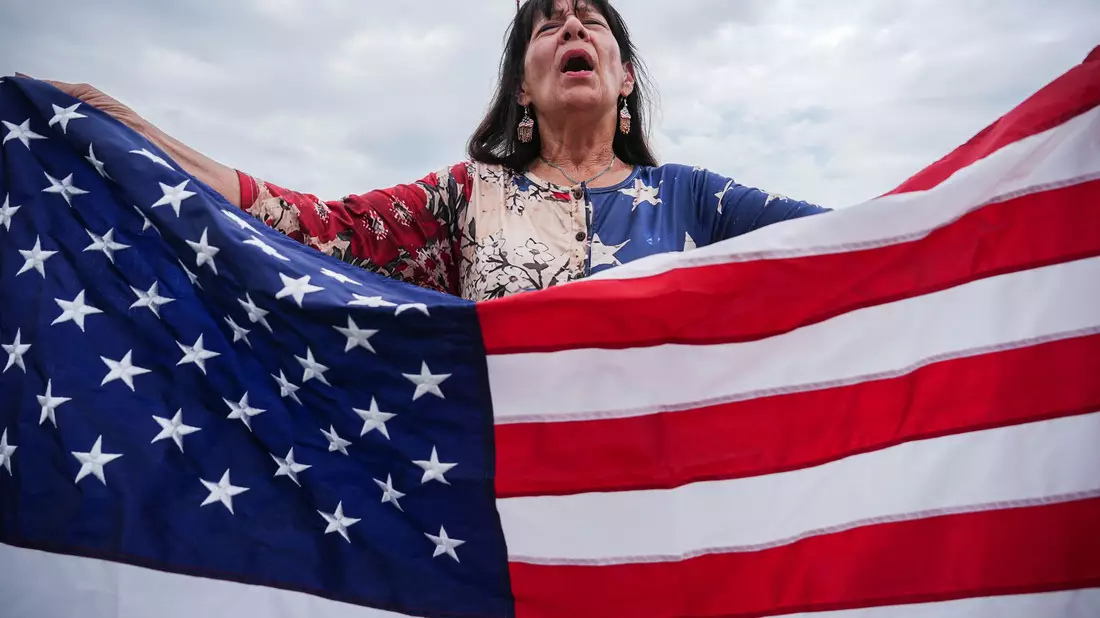 Viele Teilnehmer haben US-Flaggen bei sich.  - Bild: Julia Demaree Nikhinson/AP/dpa