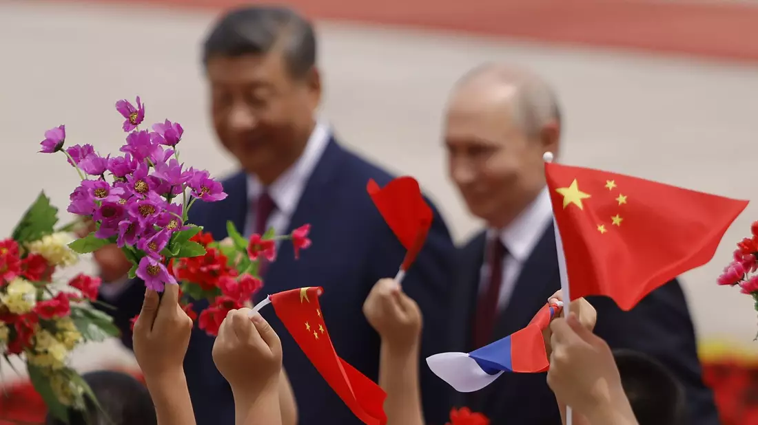 Mit Blumen und Fähnchen empfingen chinesische Kinder den Gast aus Moskau.  - Bild: Maxim Shemetov/Pool Reuters/AP/dpa