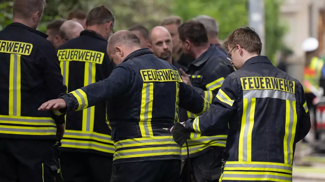 Einsatzkräfte der Feuerwehr reinigen während einer Pause ihre Arbeitsschutzkleidung am Einsatzort. - Bild: Sebastian Kahnert/dpa