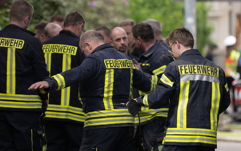Einsatzkräfte der Feuerwehr reinigen während einer Pause ihre Arbeitsschutzkleidung am Einsatzort. - Foto: Sebastian Kahnert/dpa