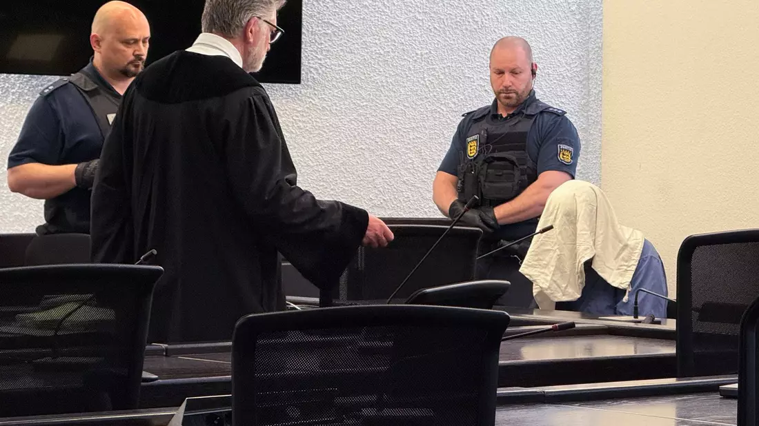 Der Angeklagte kam mit verdecktem Gesicht in den Gerichtssaal.  - Bild: David Nau/dpa