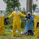 Mitarbeiter des Roten Kreuzes in Schutzkleidung desinfizieren sich. - Foto: Moses Sawasawa/AP/dpa