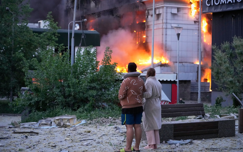 Menschen in Kiew beobachten ein brennendes Gebäude nach einem russischen Raketenangriff. - Foto: Efrem Lukatsky/AP/dpa
