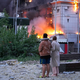Menschen in Kiew beobachten ein brennendes Gebäude nach einem russischen Raketenangriff. - Foto: Efrem Lukatsky/AP/dpa