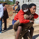 Ein Helfer trägt eine verletzte Schülerin. - Foto: Andrew Kasuku/AP/dpa