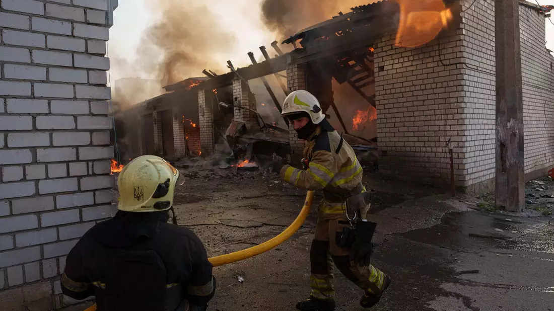 Rettungskräfte löschen ein Feuer in einer Kiewer Autowerkstatt, die durch einen russischen Angriff beschädigt wurde. - Bild: Evgeniy Maloletka/AP/dpa