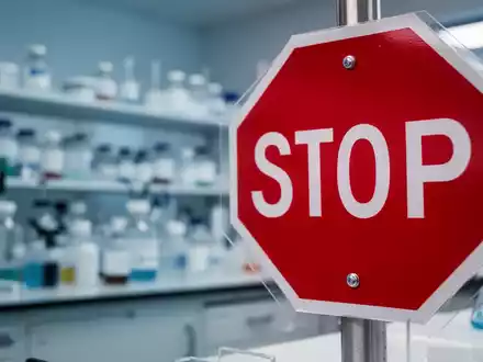 Ein rotes Stoppschild im Vordergrund, vor einem verschwommenen pharmazeutischen Laborhintergrund. - Foto: über boerse-global.de
