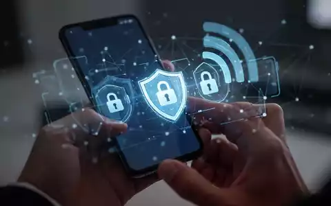 Ein Smartphone-Bildschirm zeigt digitale Sicherheits-Icons wie ein Schild und ein Schloss, während im Hintergrund ein Mobilfunknetz angedeutet wird. - Foto: über boerse-global.de