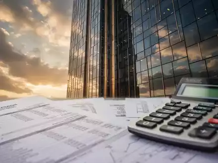 Eine Nahaufnahme der modernen Fassade eines luxuriösen Hochhauses, die den Himmel widerspiegelt, mit verschwommenen Finanzdokumenten im Vordergrund. - Foto: über boerse-global.de