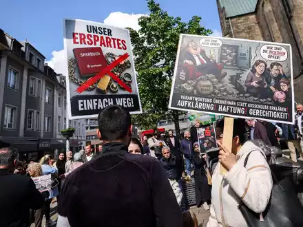 «Unser Erspartes - einfach weg», klagten geschädigte Sparkassenkunden Anfang Mai bei einer Kundgebung in Gelsenkirchen. Jetzt beginnen die ersten Zivilprozesse gegen die Sparkasse. (Archivbild) - Foto: Christoph Reichwein/dpa