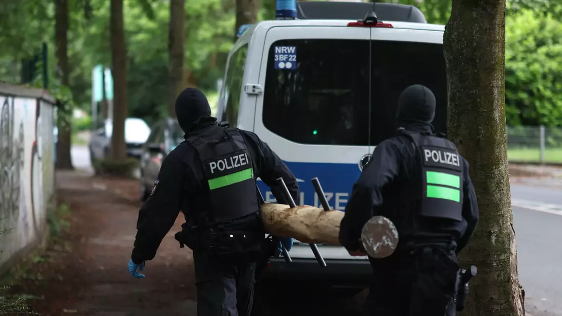 Polizisten tragen einen Rammbock. - Bild: Christoph Reichwein/dpa