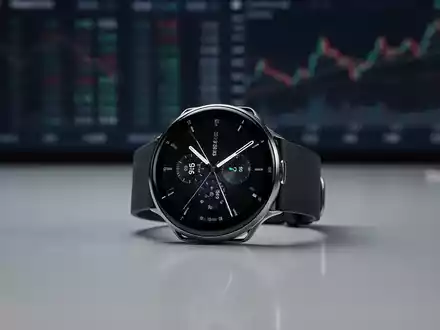 Eine schlanke, dünne Smartwatch auf einer reflektierenden Oberfläche mit unscharfem Finanzmarkt-Hintergrund. - Foto: über boerse-global.de