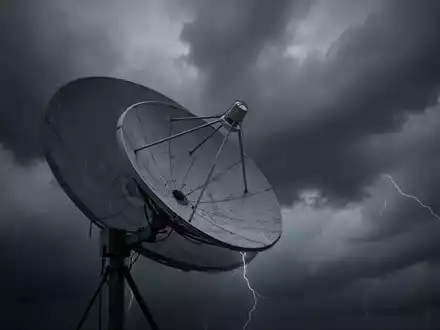 Eine Satellitenschüssel zeigt nach unten, teilweise verdeckt von dunklen, stürmischen Wolken, die einen Abschwung symbolisieren. - Foto: über boerse-global.de