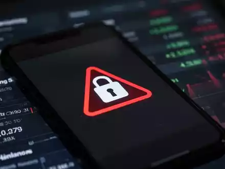 A smartphone screen with a prominent warning symbol, overlaid on a blurred background of a digital banking interface, symbolizing mobile security risks. - Foto: über boerse-global.de
