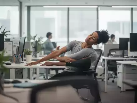 Ein Büroangestellter macht eine leichte Yoga-Übung an seinem Schreibtisch, um Rückenschmerzen vorzubeugen. - Foto: über boerse-global.de