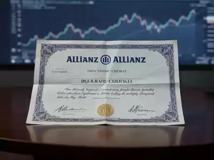 Ein Allianz-Aktienzertifikat liegt auf einem dunklen Schreibtisch, im Hintergrund eine verschwommene Kursgrafik. - Foto: über boerse-global.de