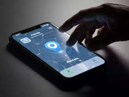 A lost iPhone displaying the 'Find My' app, with a shadowy hand reaching towards it, symbolizing both recovery and threat. - Foto: über boerse-global.de