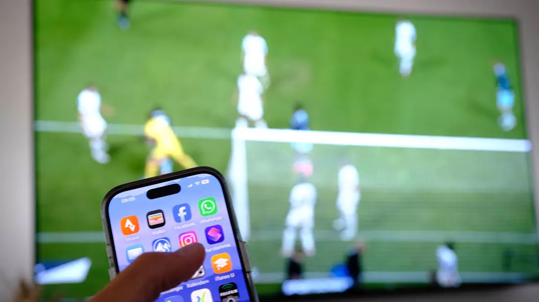 Nebenbei mal daddeln: Während das Fußballspiel läuft, schauen viele Zuschauer nebenbei aufs Handy. (Symbolbild) - Bild: Bernd Weißbrod/dpa