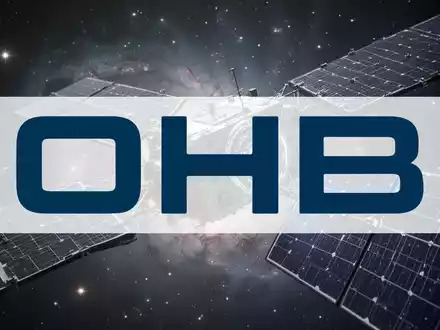 Ein detaillierter Blick auf einen modernen Satelliten mit ausgebreiteten Solarpaneelen vor einem Hintergrund aus Sternen und Nebeln. - Foto: über boerse-global.de