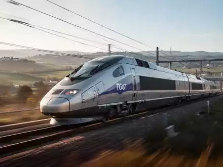 Ein moderner Hochgeschwindigkeitszug, ähnlich dem TGV M, rast durch eine europäische Landschaft mit Hügeln und Infrastruktur. - Foto: über boerse-global.de