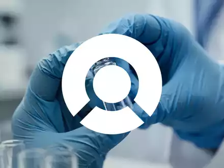 Hände eines Wissenschaftlers in blauen Handschuhen, die in einem Labor vorsichtig ein Medikamentenfläschchen halten. - Foto: über boerse-global.de
