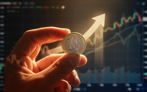 Nahaufnahme einer Hand, die eine Euro-Münze hält, mit angedeutetem Aufwärtspfeil und verschwommenen Finanzdiagrammen im Hintergrund. - Foto: über boerse-global.de