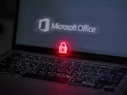 A close-up of a MacBook keyboard with a fading Microsoft Office logo on the screen and a red glowing security certificate icon. - Foto: über boerse-global.de