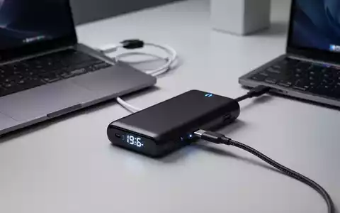 A sleek, black high-capacity laptop power bank with an integrated braided USB-C cable charging a modern laptop. - Foto: über boerse-global.de