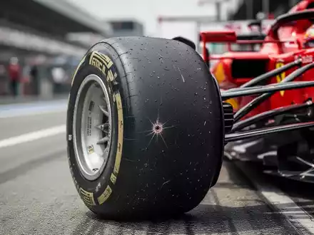 Nahaufnahme eines beschädigten Reifens eines Ferrari Formel-1-Wagens, mit verschwommenem Hintergrund der Rennstrecke. - Foto: über boerse-global.de
