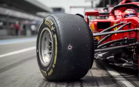 Nahaufnahme eines beschädigten Reifens eines Ferrari Formel-1-Wagens, mit verschwommenem Hintergrund der Rennstrecke. - Foto: über boerse-global.de