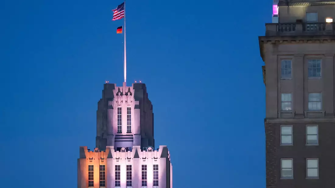 Auf einem Hochhaus in Winston-Salem weht unter der US-Fahne eine deutsche Fahne.  - Bild: Jan Woitas/dpa