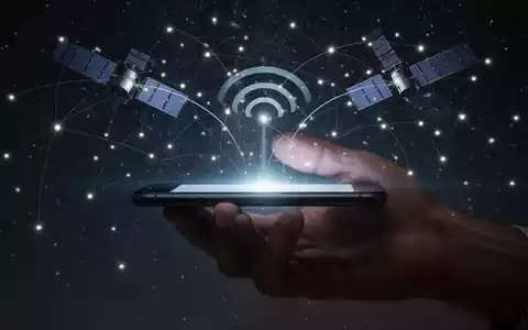 A smartphone held in a hand, with glowing lines connecting its screen to a network of satellites in a dark sky. - Foto: über boerse-global.de