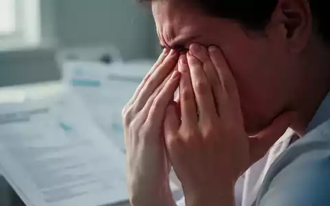 Hände einer Person, die sanft die Schläfen berühren, als Symbol für chronische Schmerzen und Erschöpfung bei Fibromyalgie. - Foto: über boerse-global.de