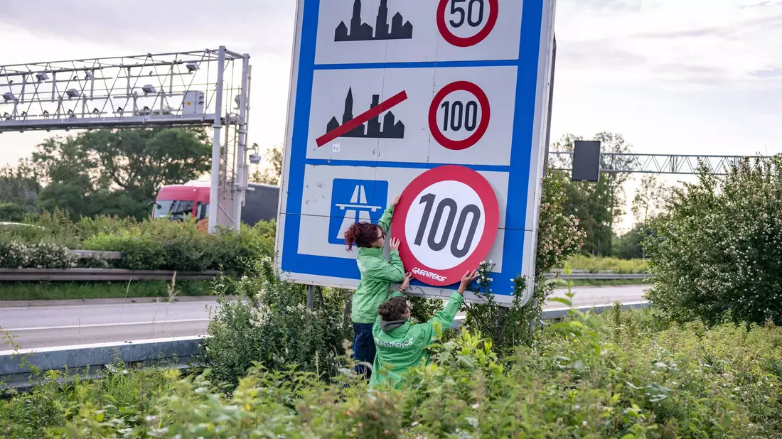 Auf Autobahnen gilt ... ein Tempo-100-Tempolimit? So zumindest wollen es Greenpeace-Aktivistinnen, hier bei der Aktion am Montagmorgen in Aachen.  - Bild: Benjamin Westhoff/dpa