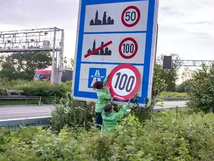 Auf Autobahnen gilt ... ein Tempo-100-Tempolimit? So zumindest wollen es Greenpeace-Aktivistinnen, hier bei der Aktion am Montagmorgen in Aachen. - Foto: Benjamin Westhoff/dpa