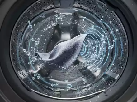 Nahaufnahme einer Waschmaschinentrommel mit Wasser und Stoff, die moderne, ressourcenschonende Reinigungstechnologien symbolisiert. - Foto: über boerse-global.de