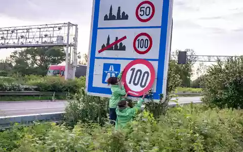 Auf Autobahnen gilt ... ein Tempo-100-Tempolimit? So zumindest wollen es Greenpeace-Aktivistinnen, hier bei der Aktion am Montagmorgen in Aachen.  - Bild: Benjamin Westhoff/dpa