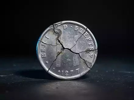 Eine einzelne, angelaufene und rissige Silbermünze liegt auf einem dunklen Hintergrund mit dramatischen Schatten. - Foto: über boerse-global.de
