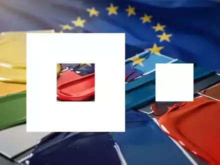 Nahaufnahme von glänzenden Farbmustern, die Industrielacke darstellen, mit einer angedeuteten EU-Flagge im Hintergrund. - Foto: über boerse-global.de