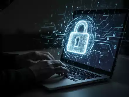 Hände tippen auf einer Laptoptastatur, mit einem leuchtenden digitalen Schloss auf dem Bildschirm, das einen Cyberangriff darstellt. - Foto: über boerse-global.de