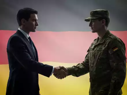 Eine Silhouette einer Geschäftsfrau im Anzug, die einem Soldaten in Uniform die Hand schüttelt, vor einem verschwommenen Hintergrund mit deutscher Flagge. - Foto: über boerse-global.de