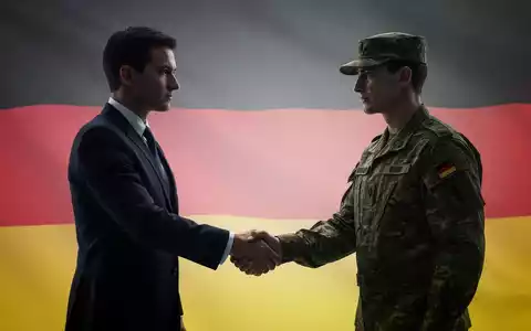 Eine Silhouette einer Geschäftsfrau im Anzug, die einem Soldaten in Uniform die Hand schüttelt, vor einem verschwommenen Hintergrund mit deutscher Flagge. - Foto: über boerse-global.de