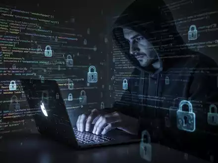 A person in a hoodie typing on a laptop, surrounded by digital security symbols, representing cybersecurity vulnerabilities. - Foto: über boerse-global.de